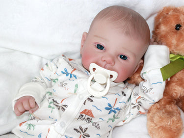 A baby doll positioned on a clean white sheet, with a pacifier, highlighting its charming design and soft textures.